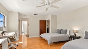 Une chambre avec deux lits, un bureau et un ventilateur de plafond.