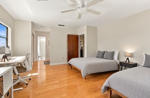 Une chambre avec deux lits, un bureau et un ventilateur de plafond.