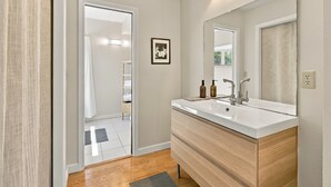 Une salle de bain moderne avec un grand miroir, deux vasques et un meuble-lavabo en bois.