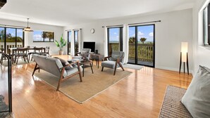 Un salon spacieux doté d’une grande fenêtre, d’un coin repas et d’un balcon offrant une vue sur l’océan.