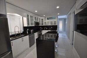 Een moderne keuken met witte kasten, zwarte aanrechtbladen en een centraal eiland.