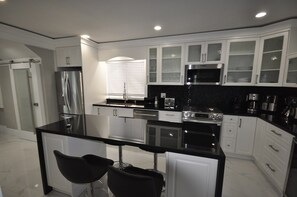 Een moderne keuken met een centraal eiland, roestvrijstalen apparatuur en witte kastjes.
