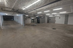 A spacious underground parking area with concrete floors, multiple parking spaces, and a central walkway. - Beautiful Luxury 3 Bed Townhouse (Vancouver)