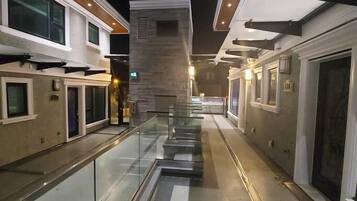 A corridor with glass railings, a central walkway, and buildings on either side.