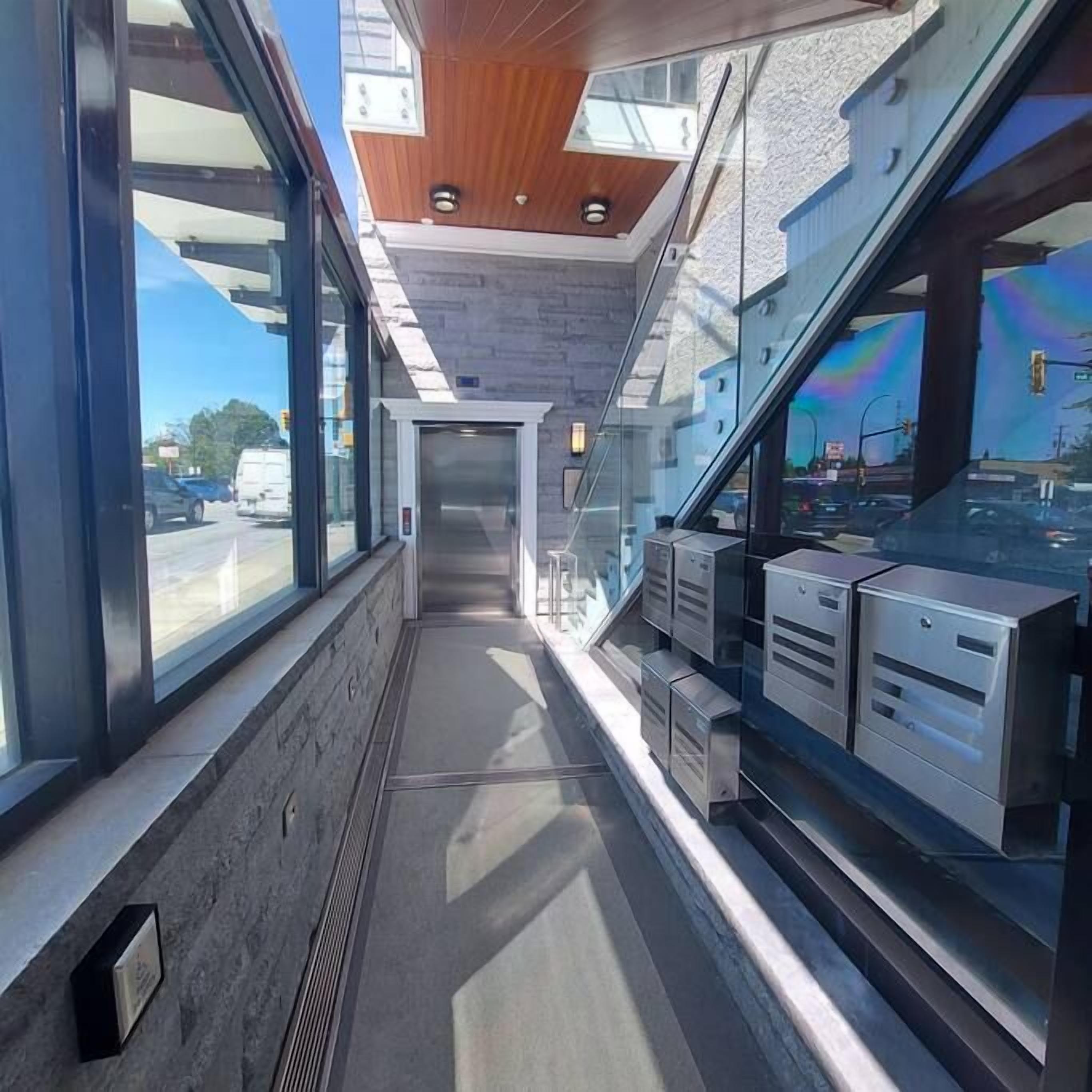 A corridor with glass walls, a wooden ceiling, and metal storage units.