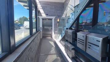 A corridor with glass walls, a wooden ceiling, and metal storage units.