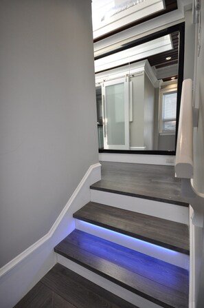 A staircase with a modern design, featuring a dark wood finish and blue LED lighting on the steps.