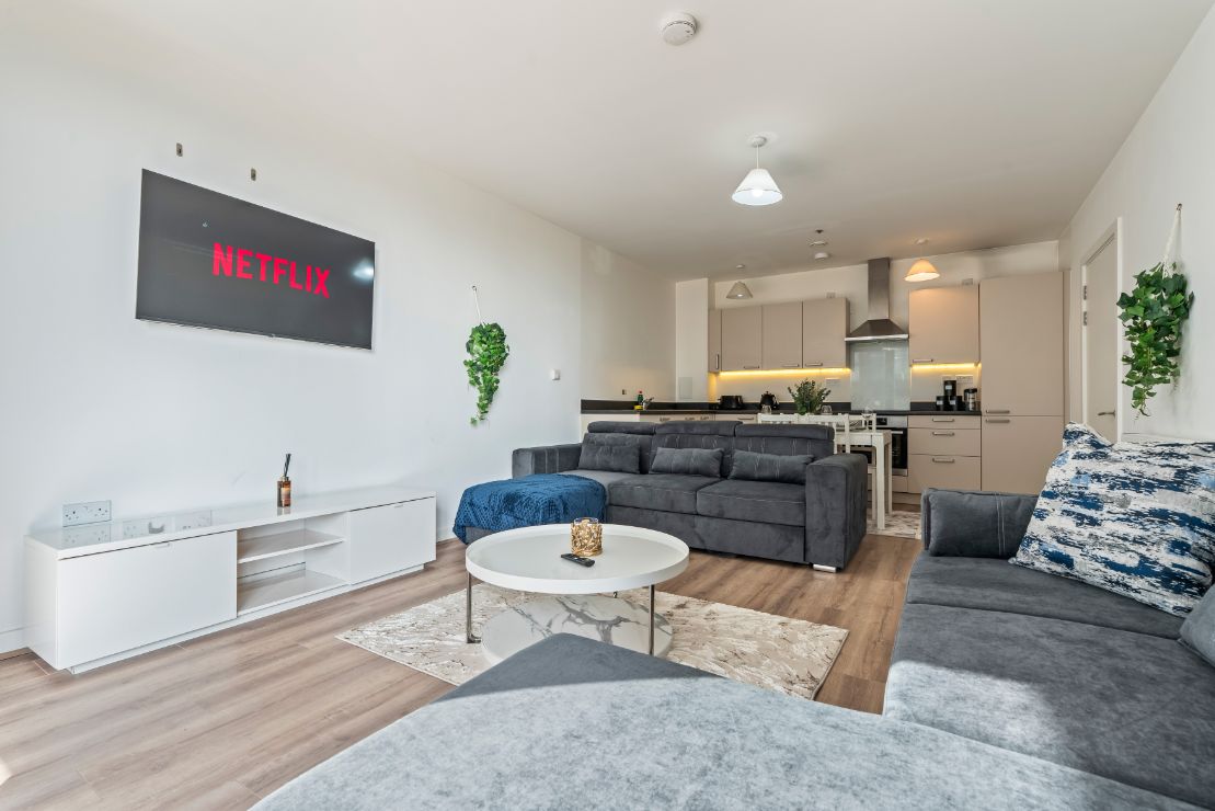 Uma sala de estar moderna com um sofá cinza, uma mesa de centro e uma TV de tela plana exibindo o logotipo da Netflix.