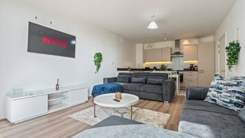 Uma sala de estar moderna com um sofá cinza, uma mesa de centro e uma TV de tela plana exibindo o logotipo da Netflix.