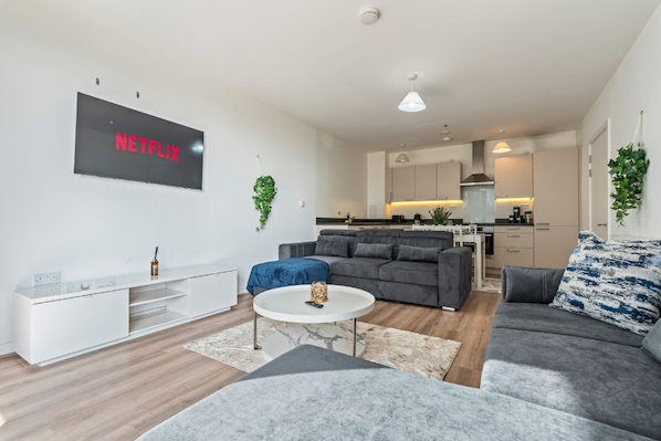 Uma sala de estar moderna com um sofá cinza, uma mesa de centro e uma TV de tela plana exibindo o logotipo da Netflix.