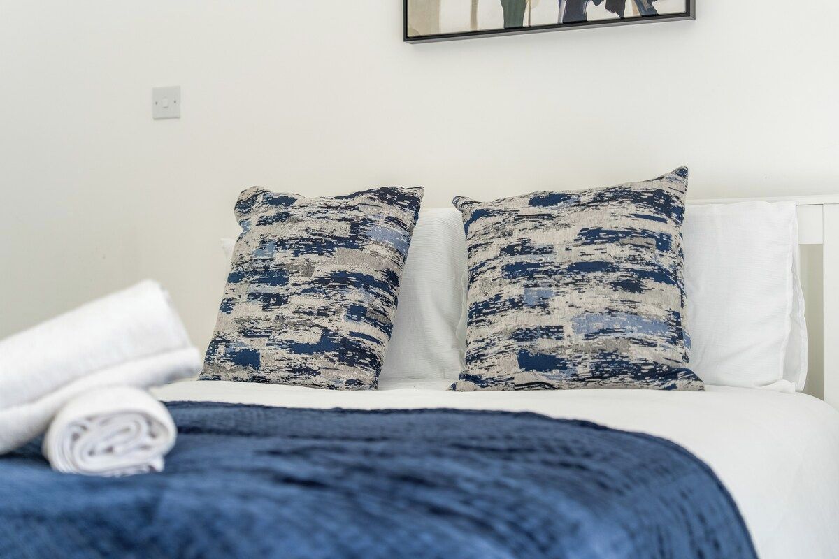 A bed with white bedding and two pillows with a blue and white pattern.