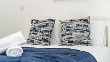 A bed with white bedding and two pillows with a blue and white pattern.