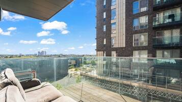 A balcony with a cushioned seating area overlooking a cityscape.