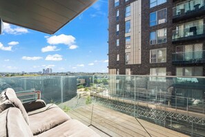 A balcony with a cushioned seating area overlooking a cityscape.
