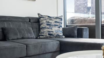 A grey sectional sofa with a patterned pillow and a white coffee table in a modern living room.