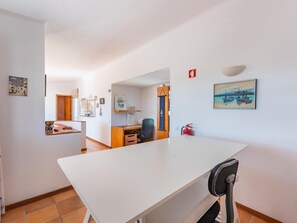 Una habitación con un escritorio blanco, una silla, un extintor y un cuadro en la pared.