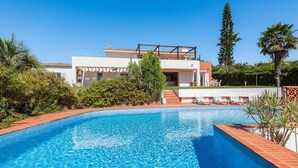 Una casa moderna con piscina, immersa nel verde e circondata da palme.