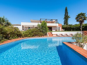 Una casa moderna con piscina, rodeada de vegetación y palmeras.