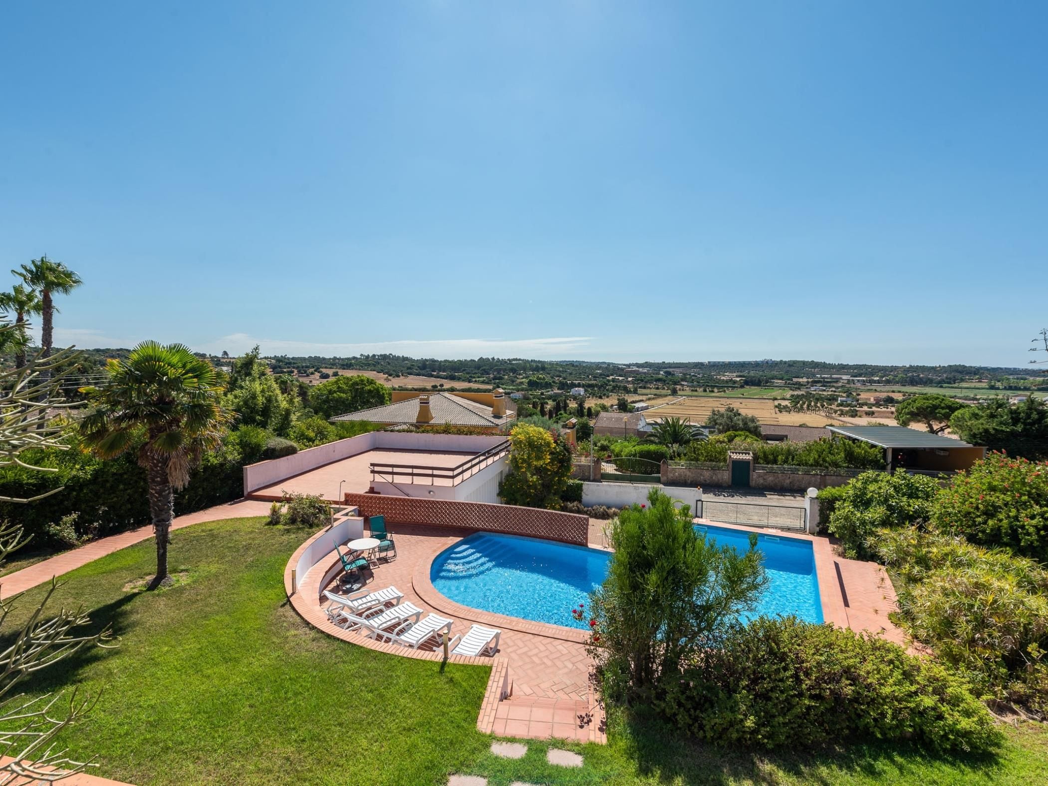 Il s’agit d’une propriété résidentielle dotée d’une piscine, d’une terrasse avec des chaises longues et offrant une vue sur le paysage environnant.