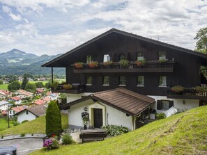 A two-story chalet with a balcony, a small attached building, and a view of a valley. - Bergschlossel WHG 19 (Oberaudorf)