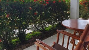 A covered outdoor seating area with a table and chairs, surrounded by lush greenery and flowering plants. - Hotel Villa Fortuna (La Fortuna)