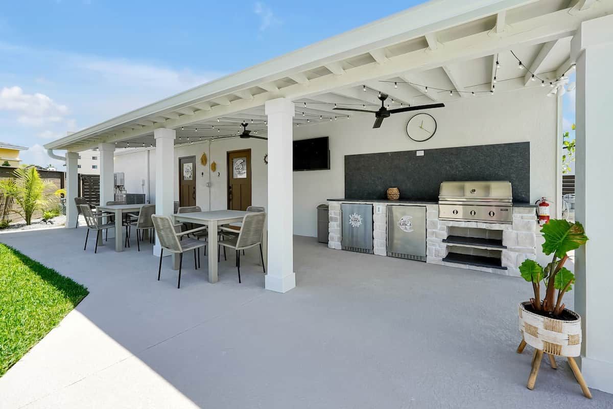 An outdoor patio with a grill, seating area, and a clock on the wall.