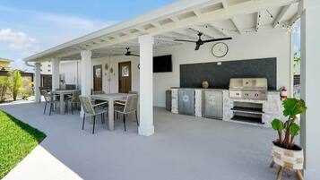 An outdoor patio with a grill, seating area, and a clock on the wall.