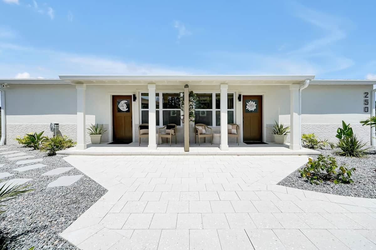 A modern building with a symmetrical facade, a central entrance with glass doors, and a paved walkway leading to it.