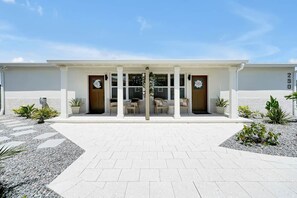 A modern building with a symmetrical facade, a central entrance with glass doors, and a paved walkway leading to it.