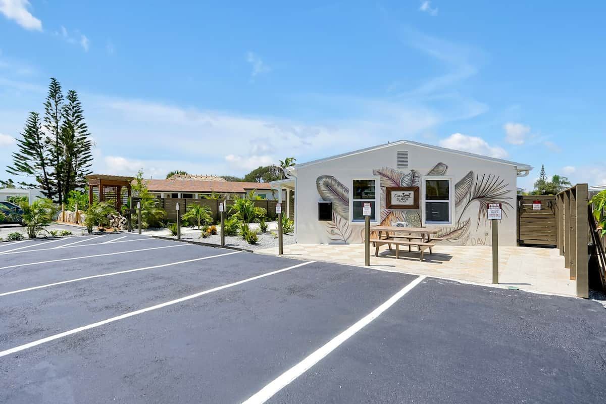A parking lot with a building that has a leaf mural and a bench.