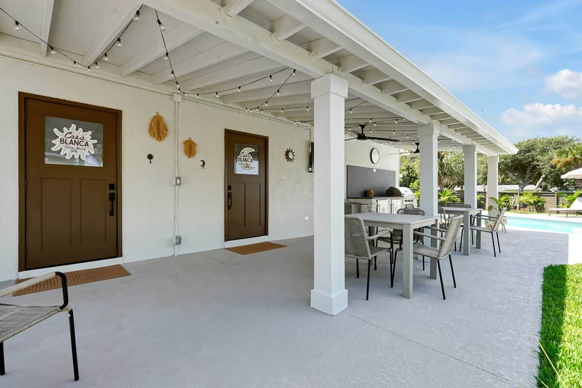 A covered outdoor area with a pool, outdoor seating, and a grill.