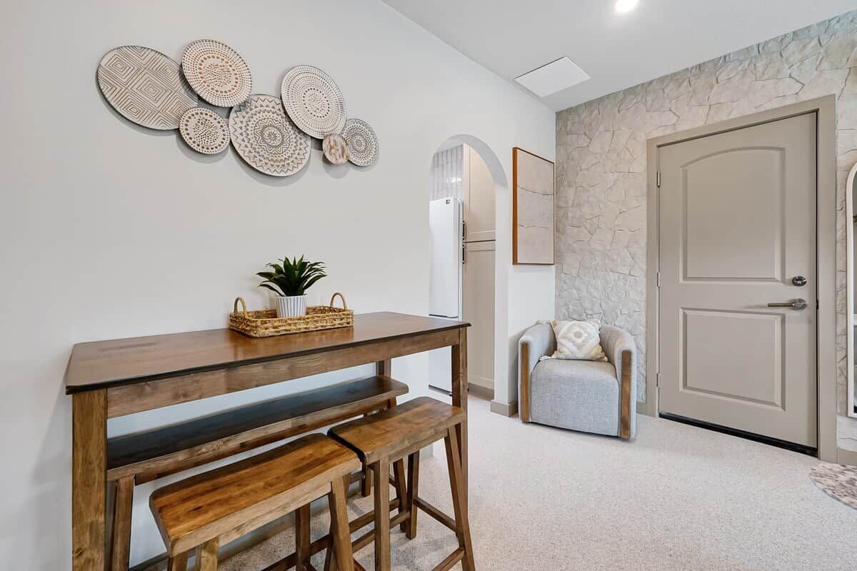 A modern interior with a wooden table and bench, decorative wall art, a grey sofa, and a door.