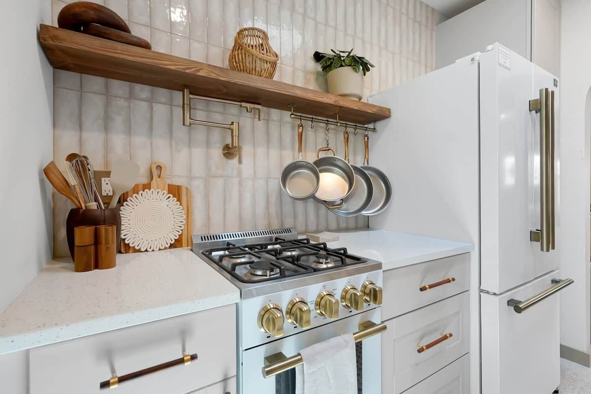 Een keuken met een gasfornuis, witte kasten en een witte koelkast.