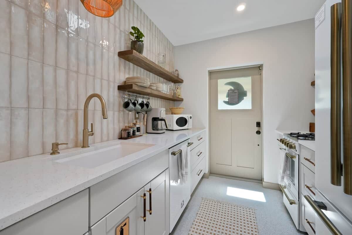 A modern kitchen with white cabinetry, a built-in oven, and a microwave.