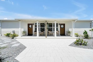 A modern building with a symmetrical facade, a central entrance with glass doors, and a paved walkway leading to it. - Casa Blanca Cocoa Beach, 2 minutes to the beach with saltwater pool! (Cocoa Beach)