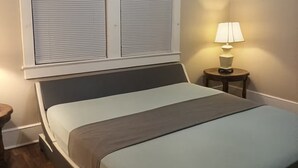 Un dormitorio con cama, mesita de noche, lámpara y ventilador de techo.