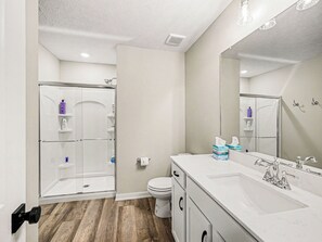 Une salle de bain équipée d’une douche, de toilettes, d’un meuble-lavabo et d’un grand miroir.