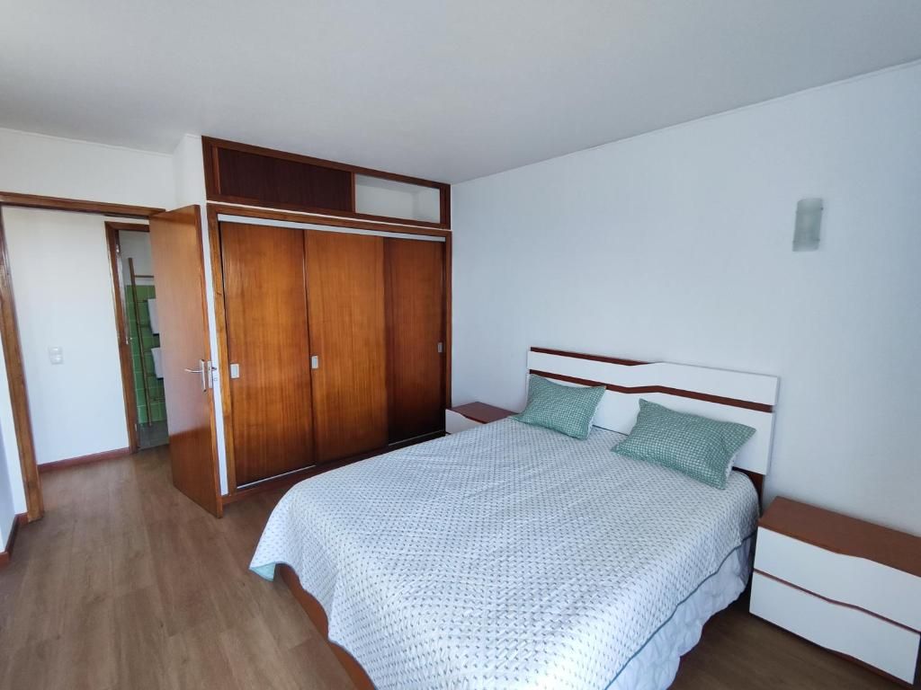 Een slaapkamer met een bed, een kledingkast en een nachtkastje.