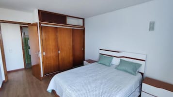 Een slaapkamer met een bed, een kledingkast en een nachtkastje.