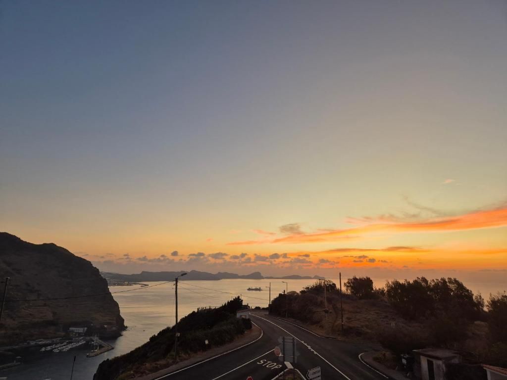 A coastal road with a stop sign, a clear sky, and a sunset.