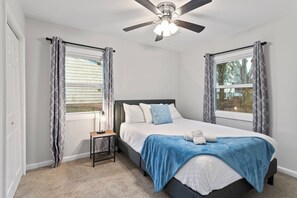 A bedroom with a bed, a nightstand, a ceiling fan, and two windows with curtains. - Cozy Decatur Oasis | 3BR + Yard | Emory & CDC (Decatur)