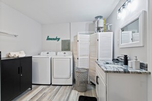 A laundry room with a washing machine, dryer, and a wall-mounted towel rack. - Cozy Decatur Oasis | 3BR + Yard | Emory & CDC (Decatur)