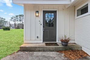 A house with a dark front door, a small porch, and a potted plant beside the entrance. - Cozy Decatur Oasis | 3BR + Yard | Emory & CDC (Decatur)