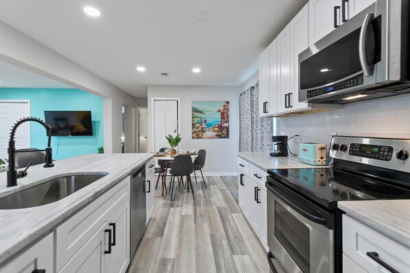 A modern kitchen with white cabinetry, stainless steel appliances, and a dining area with a table and chairs.