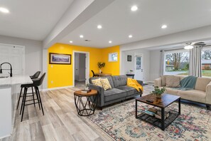 A modern living room with a grey sofa, a coffee table, and a patterned rug.