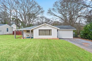A single-story house with a covered porch, a small attached garage, and a well-maintained lawn.