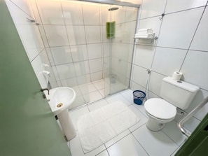 Une salle de bain avec douche, toilettes, lavabo et un mur végétal.