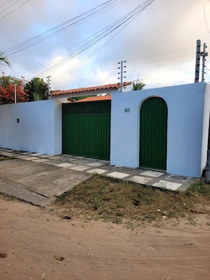 Una propietat tancada amb una porta numerada, un camí de formigó i una zona enjardinada.