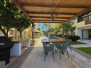 An outdoor patio with a pool, covered seating area, and a barbecue grill. - Enjoy swimming pools, a rooftop area with a Jacuzzi, and a BBQ grill. (Mazatlán)