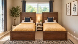 A bedroom with two wooden beds, a ceiling fan, a window with curtains, a nightstand with a lamp, and a potted plant. - 5-Acre Ranch Retreat with Pool near Medical Center & NASA (Rosharon)